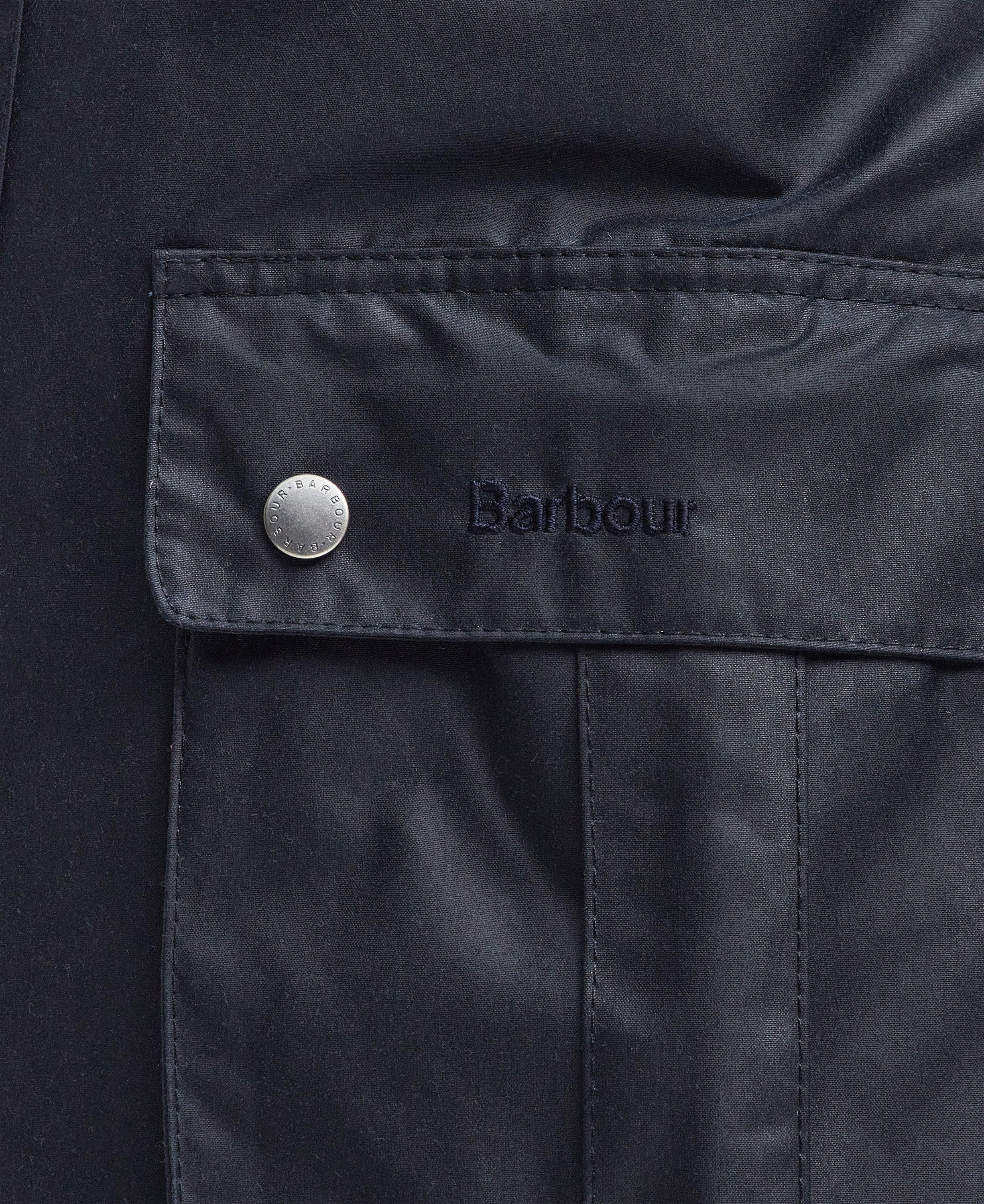 dettaglio tasca giacca cerata blu navy con bottone metallico e logo Barbour ricamato