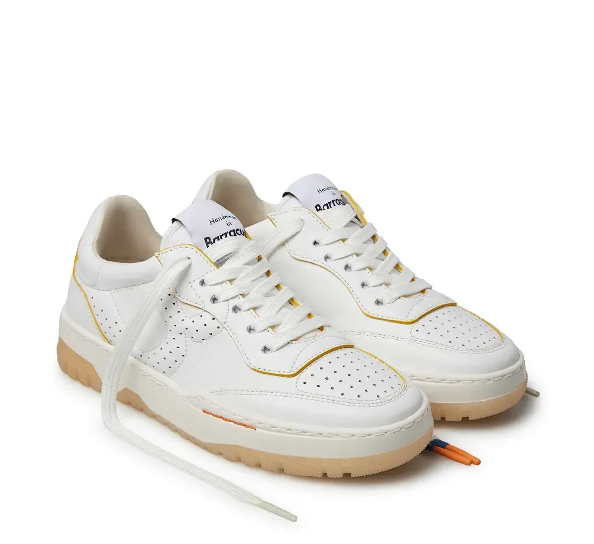 Sneakers bianche da uomo in pelle con dettagli gialli, suola beige e punta traforata.