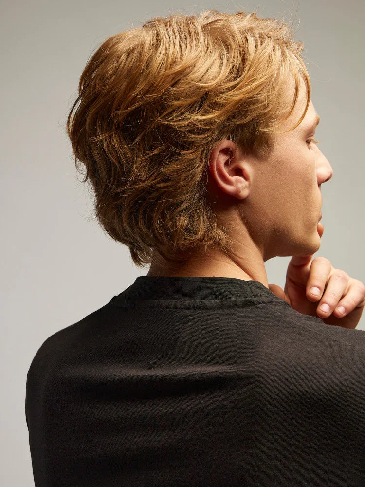 uomo di profilo con capelli biondi e maglia nera, moda abbigliamento uomo elegante