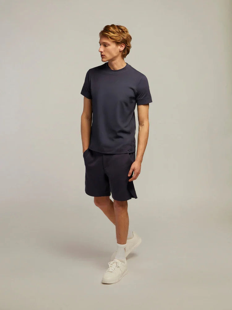 Modello uomo con t-shirt e shorts blu scuro, look casual estivo, scarpe bianche