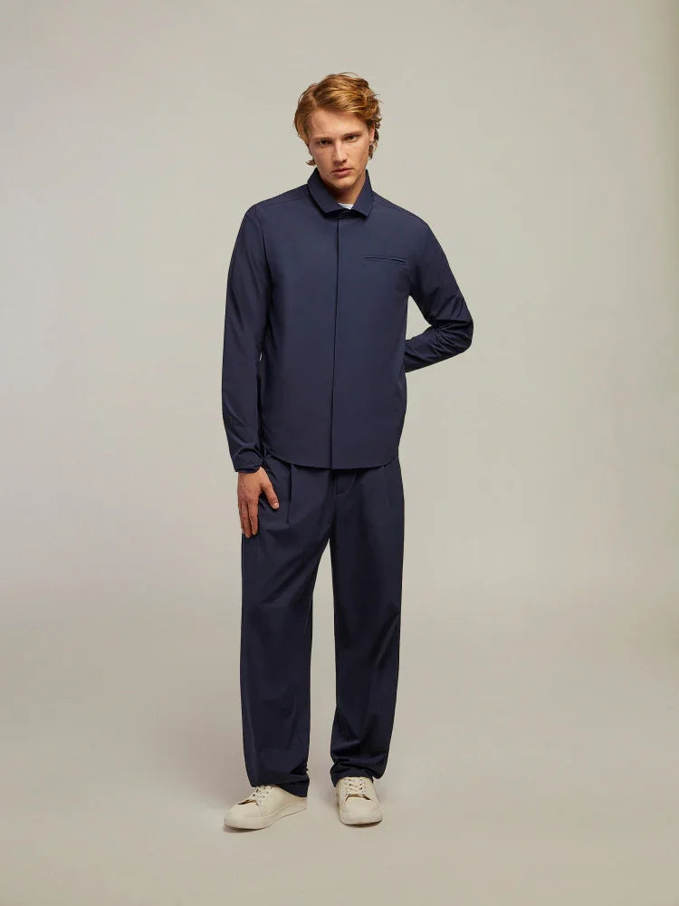 Modello indossa completo uomo blu scuro elegante con camicia e pantaloni, scarpe chiare.