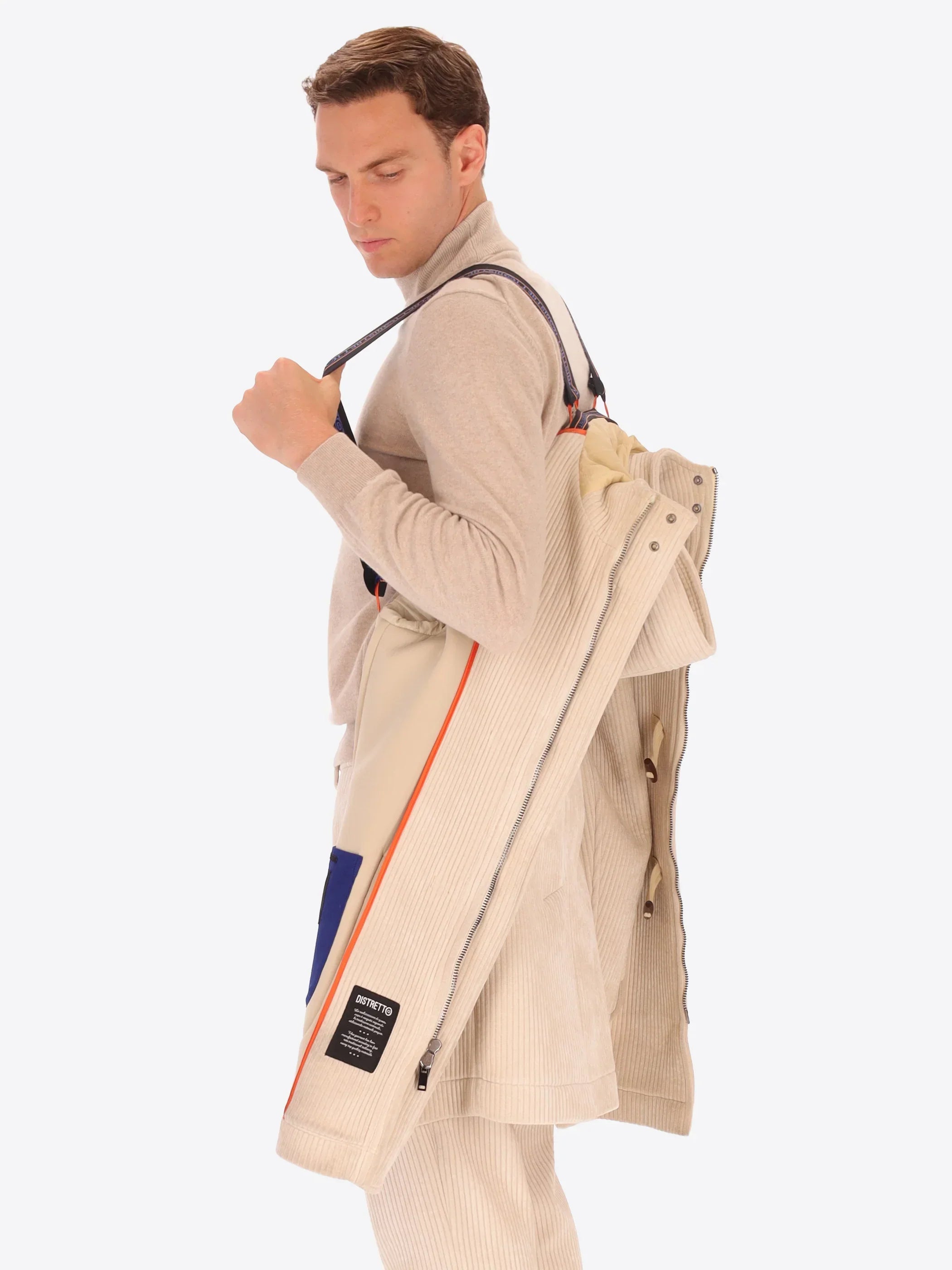 Uomo con cappotto beige in velluto a coste indossato a tracolla, abbigliamento elegante uomo.