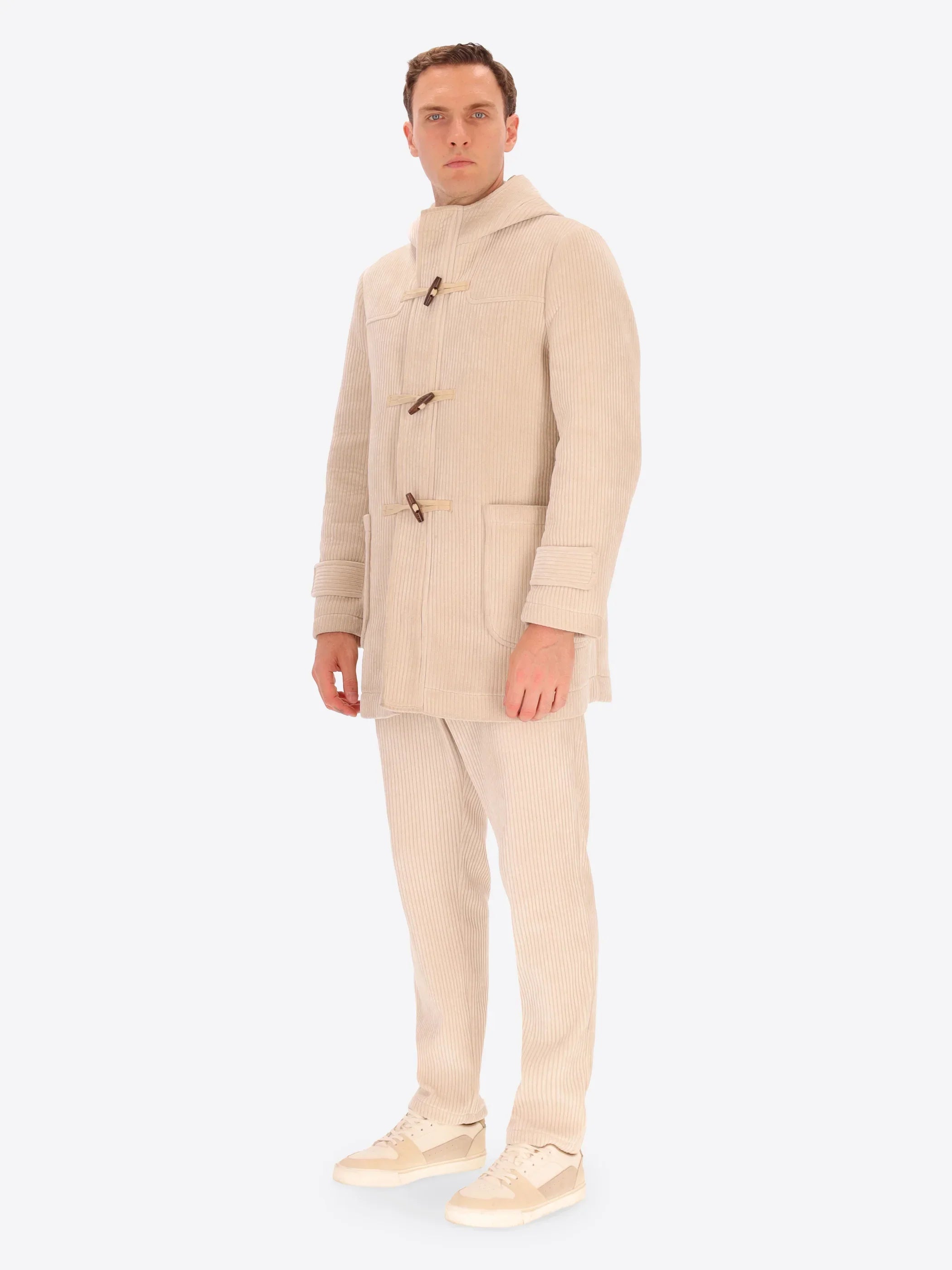Uomo con cappotto duffle beige in velluto a coste e pantaloni coordinati, stile moderno elegante