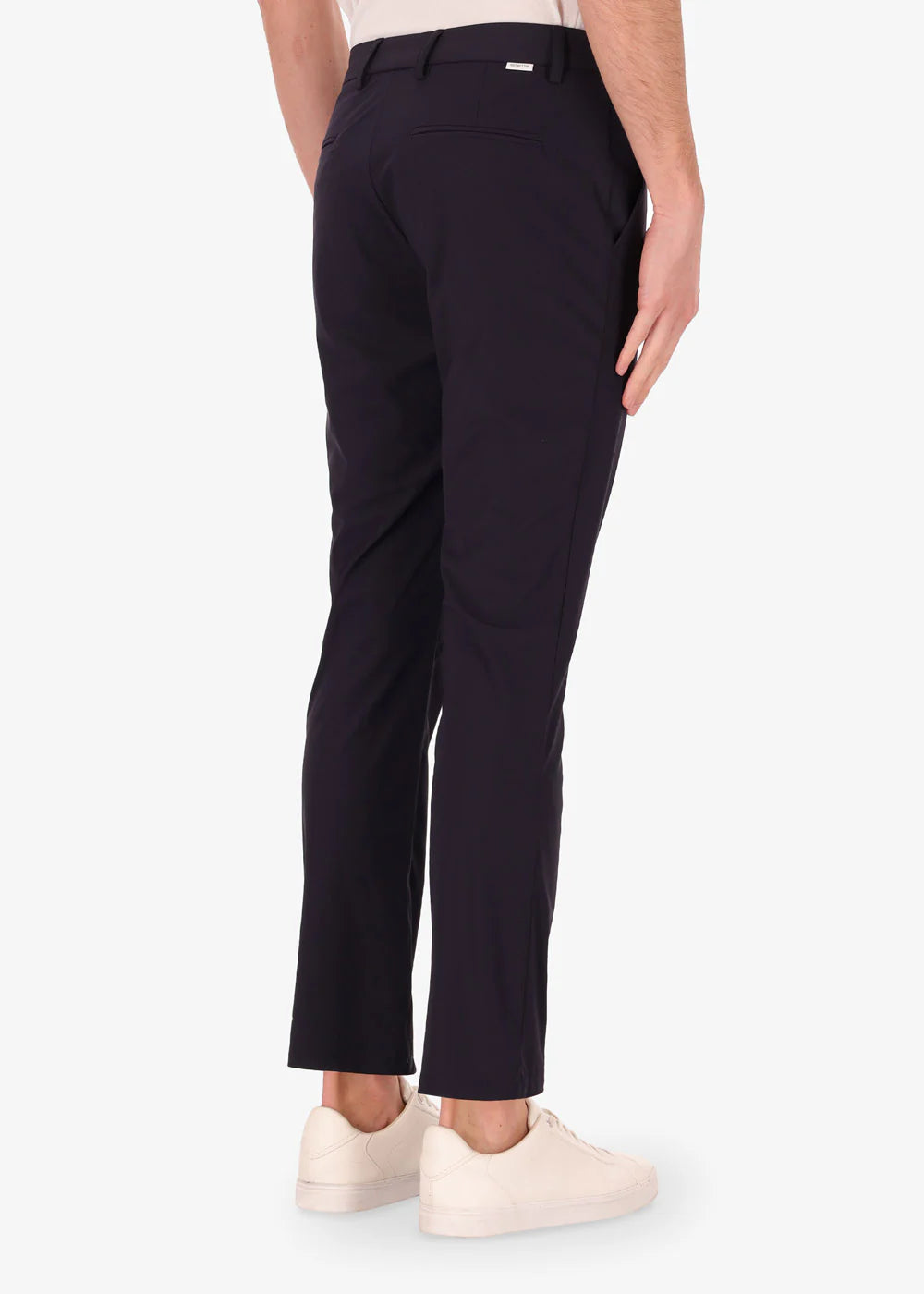 Pantaloni uomo eleganti neri slim fit, pieghe posteriori, indossati con sneakers bianche.