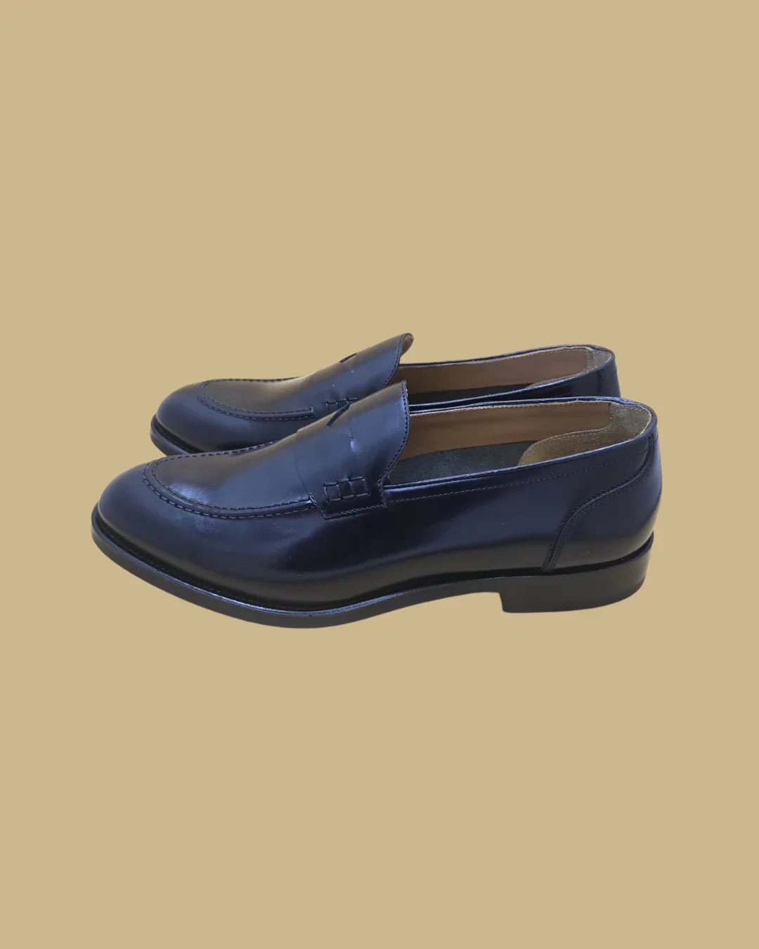 Mocassini uomo in pelle blu, stile classico, suola nera, fondo beige.