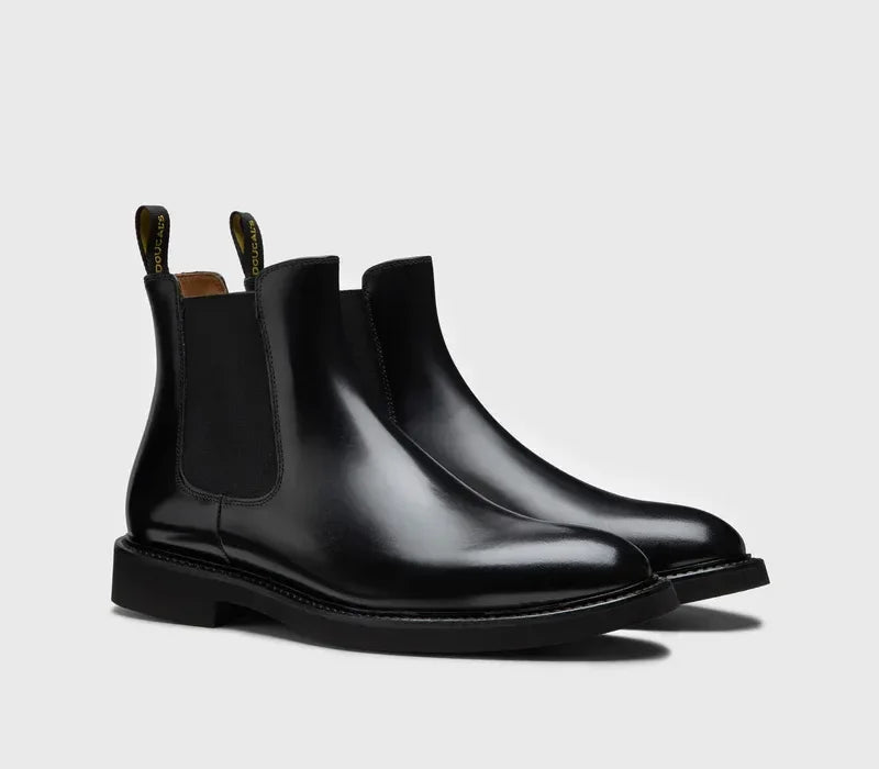 Stivaletti chelsea uomo in pelle nera lucida con elastico laterale su sfondo neutro