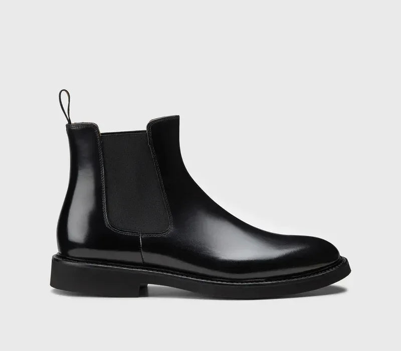 Stivaletto Chelsea uomo in pelle nera elegante, su fondo grigio chiaro.