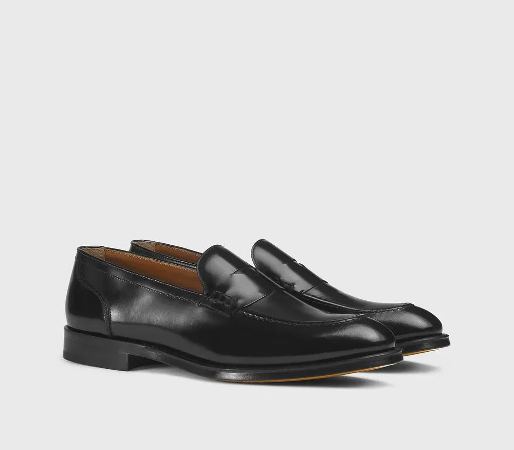Mocassini penny loafer neri da uomo in pelle lucida, eleganti, sfondo neutro.