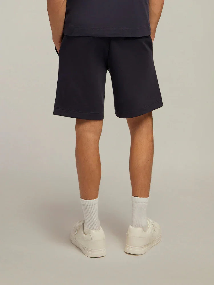 Shorts uomo blu scuro in cotone, vista posteriore, abbinati a sneakers bianche e calzini