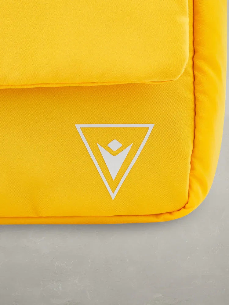 dettaglio zaino giallo con logo bianco, accessori moda uomo donna, fondo grigio
