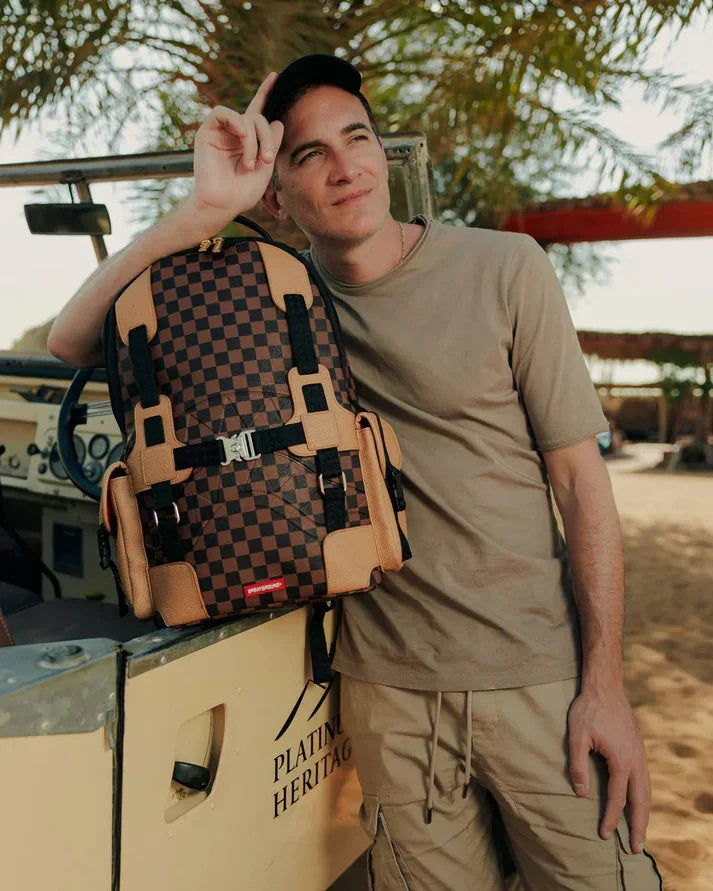 Uomo in abbigliamento casual con zaino a quadri marrone e beige, all'aperto vicino a jeep.