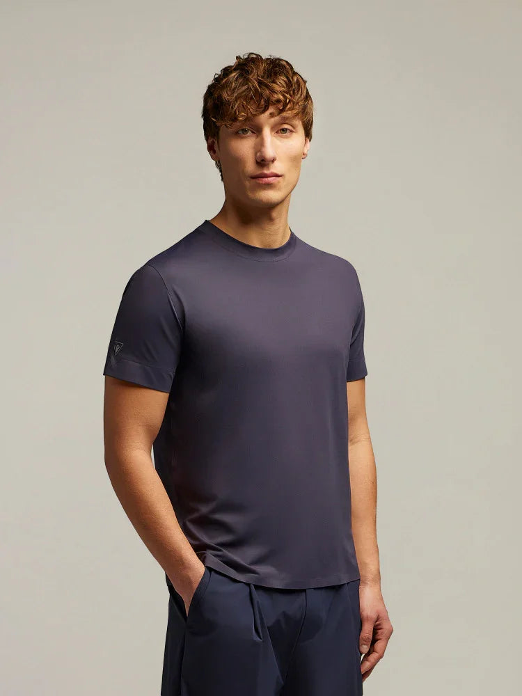 Modello uomo indossa t-shirt tecnica blu scuro e pantaloni coordinati, abbigliamento moda uomo elegante casual.