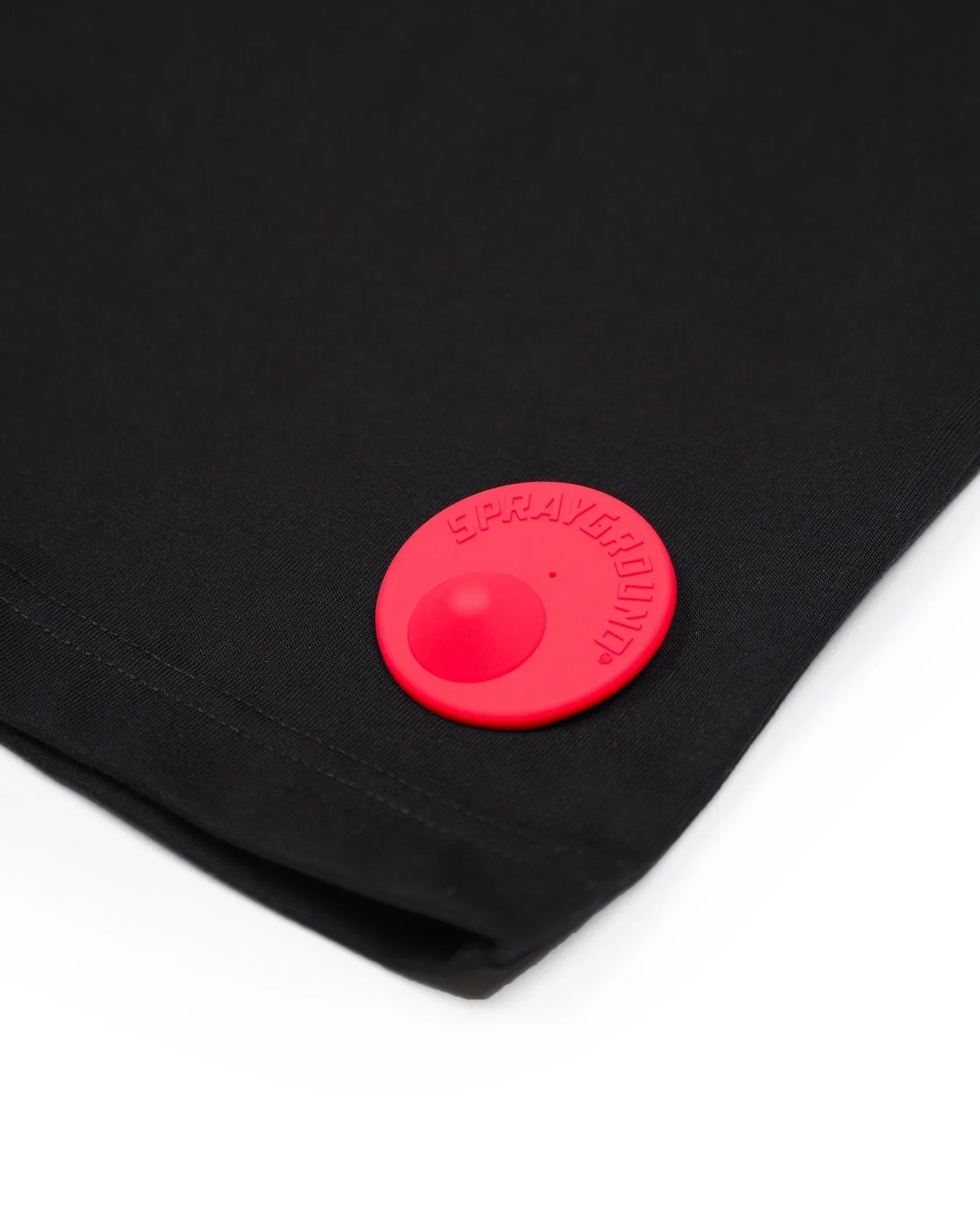 Dettaglio tessuto nero con patch rotonda rossa Sprayground, moda uomo donna.
