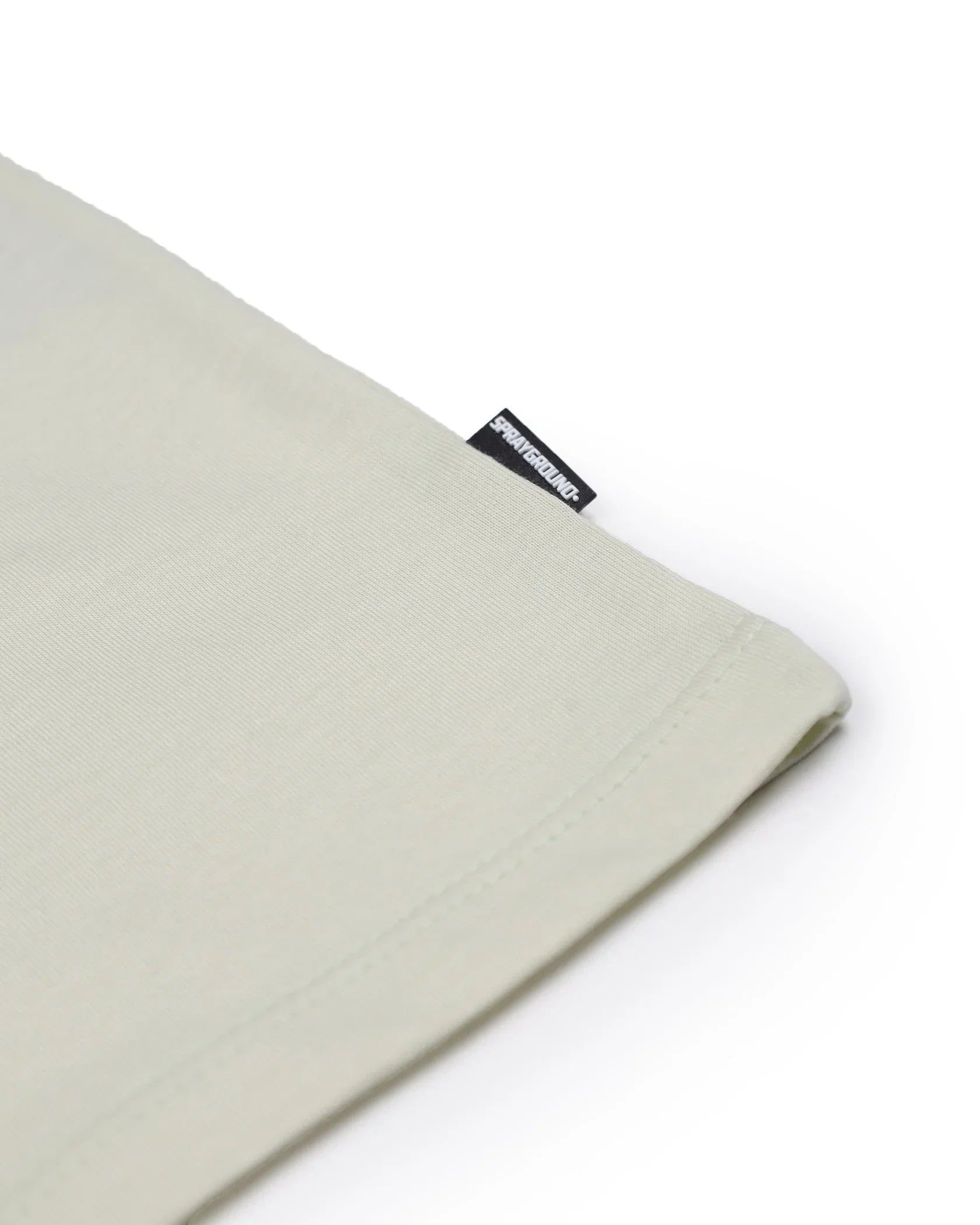 Dettaglio tessuto beige t-shirt Sprayground con etichetta laterale in evidenza