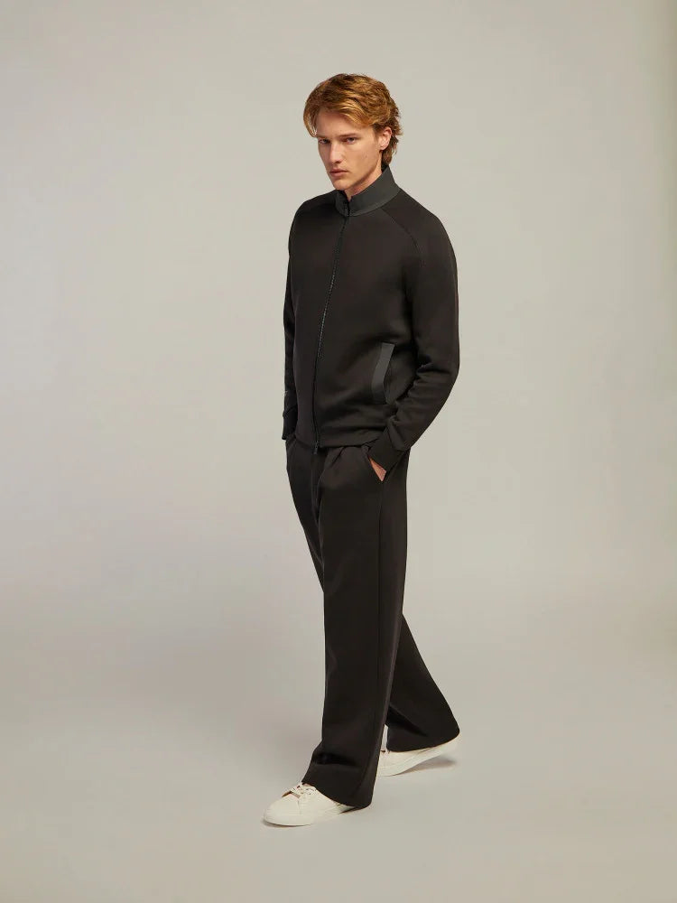 Modello uomo con tuta nera elegante e sneakers bianche su sfondo neutro