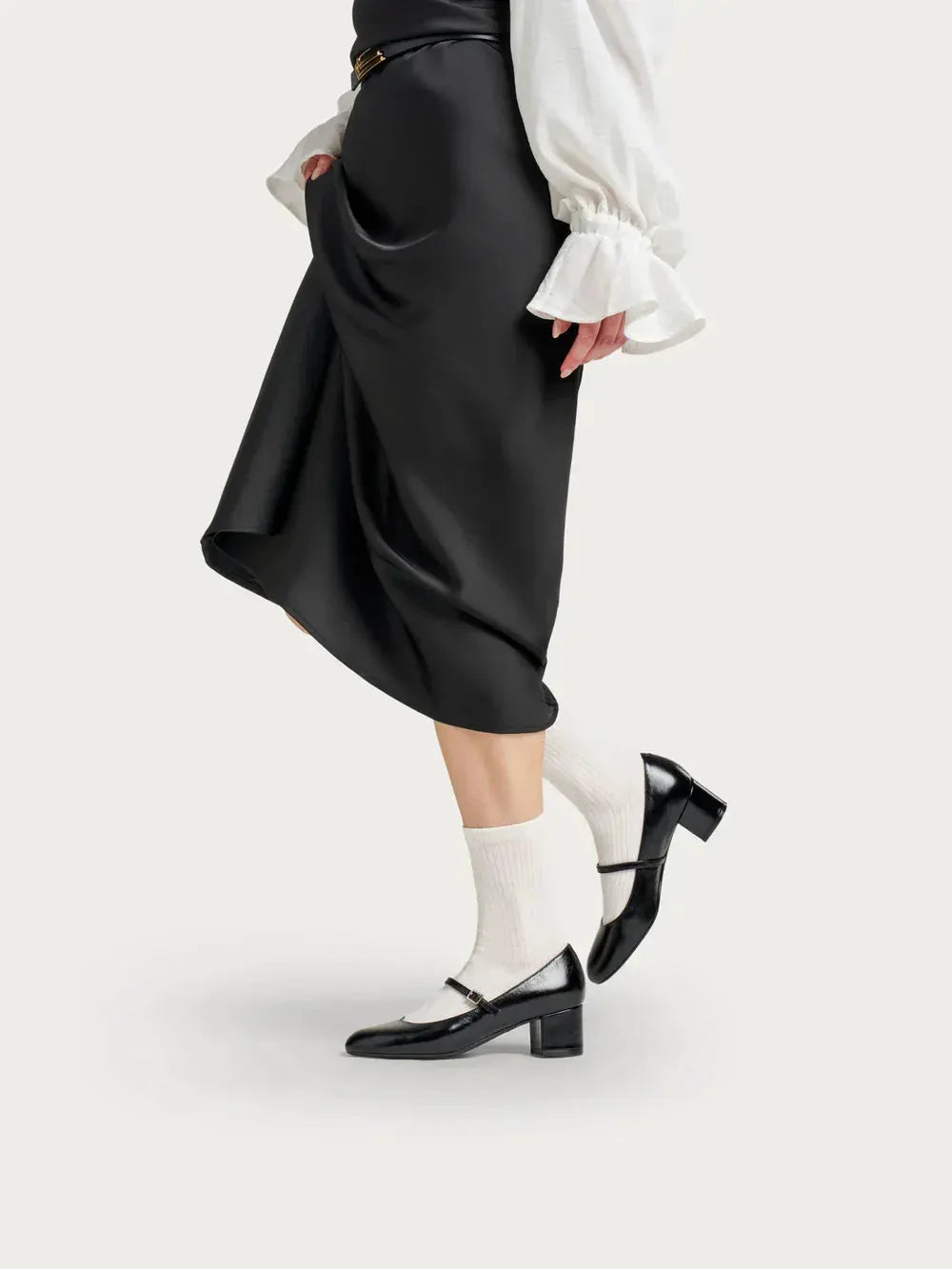 Scarpe Mary Jane nere con tacco medio indossate con calzini bianchi e gonna nera elegante
