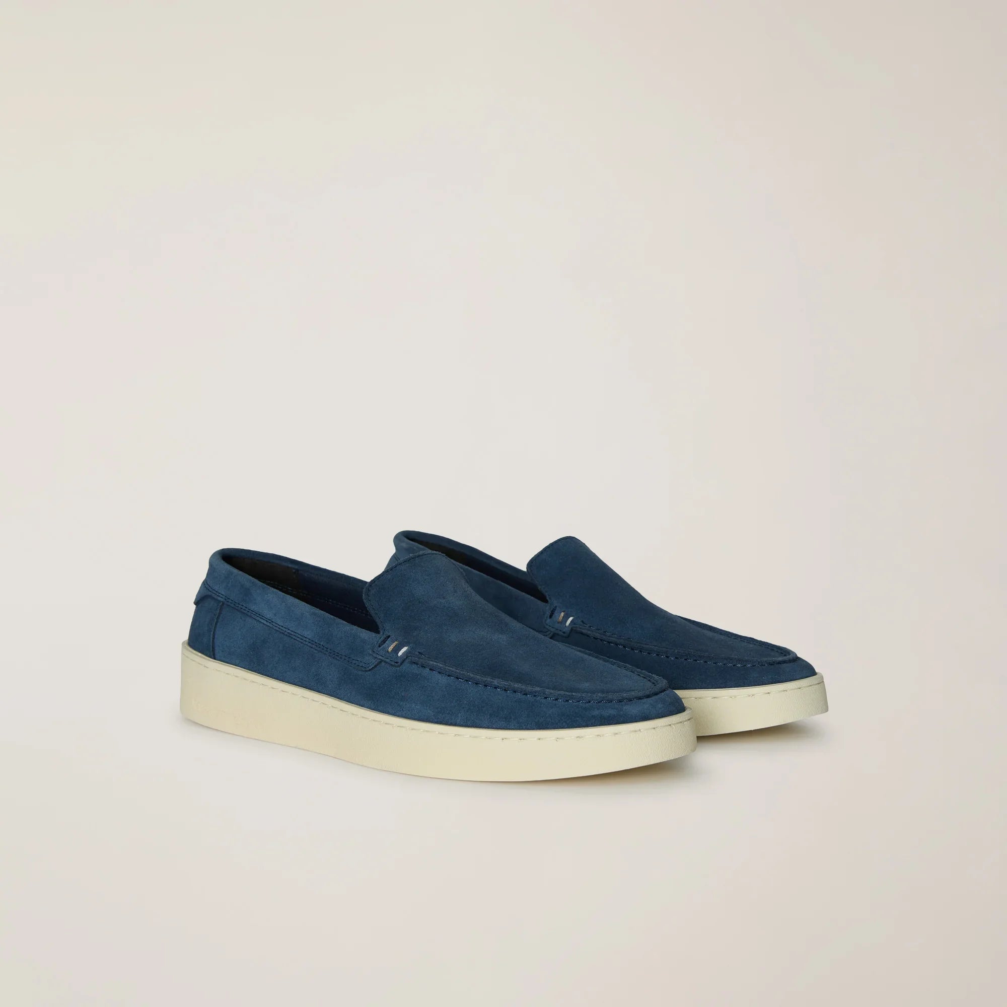 Mocassini uomo in camoscio blu con suola bianca su sfondo neutro