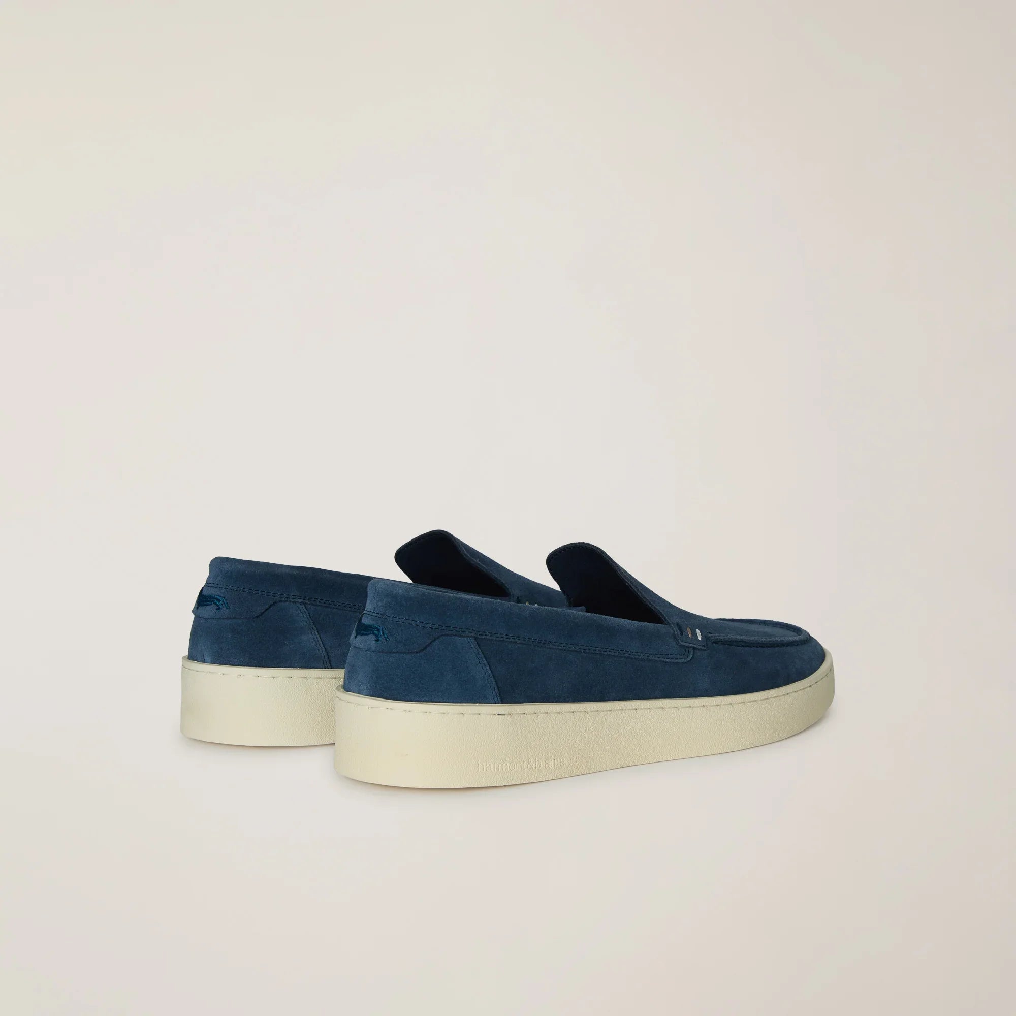 Mocassini uomo in camoscio blu con suola bianca, eleganti scarpe casual su sfondo neutro