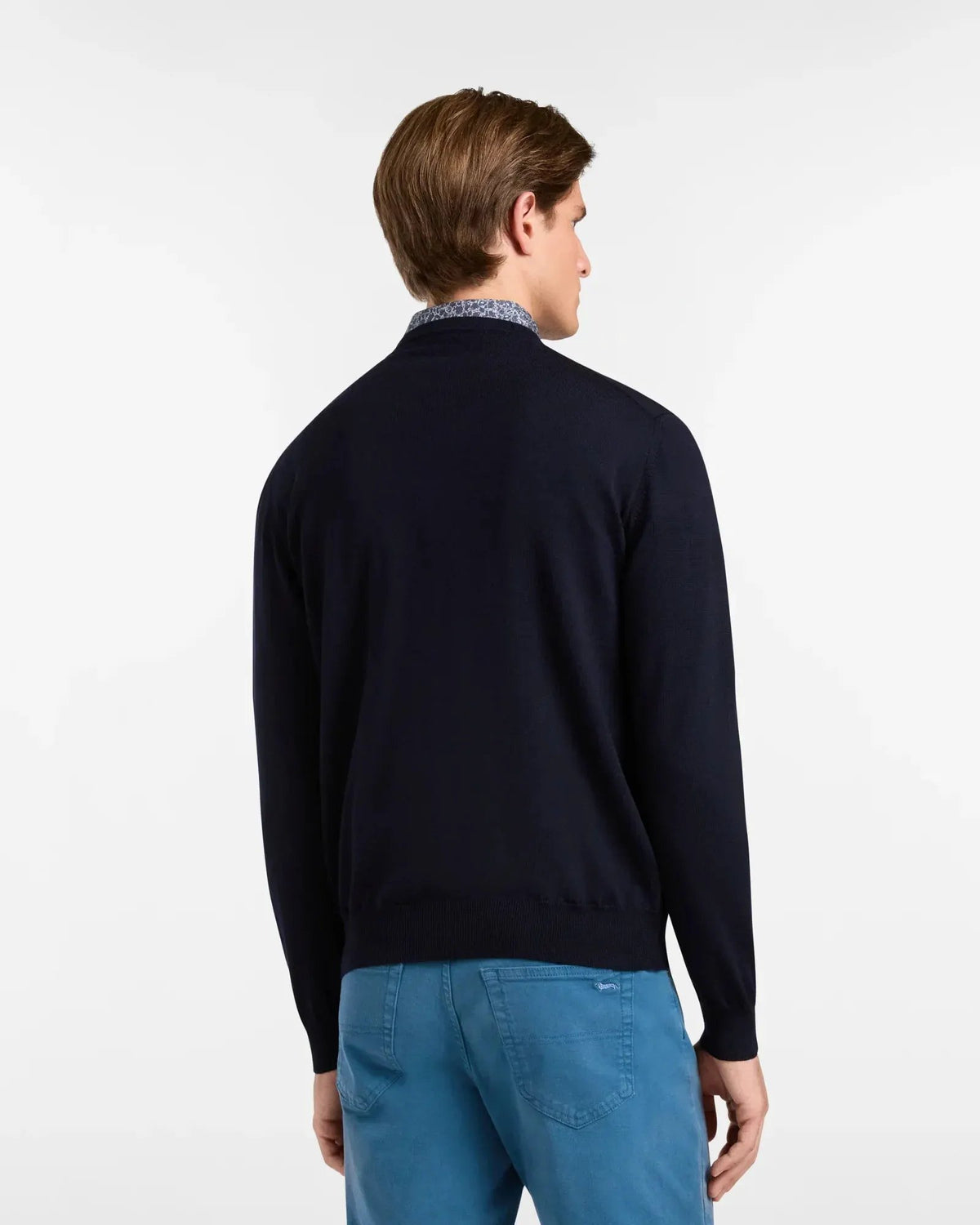 Maglione girocollo uomo blu navy in lana merino, abbinato a pantaloni azzurri, vista posteriore.