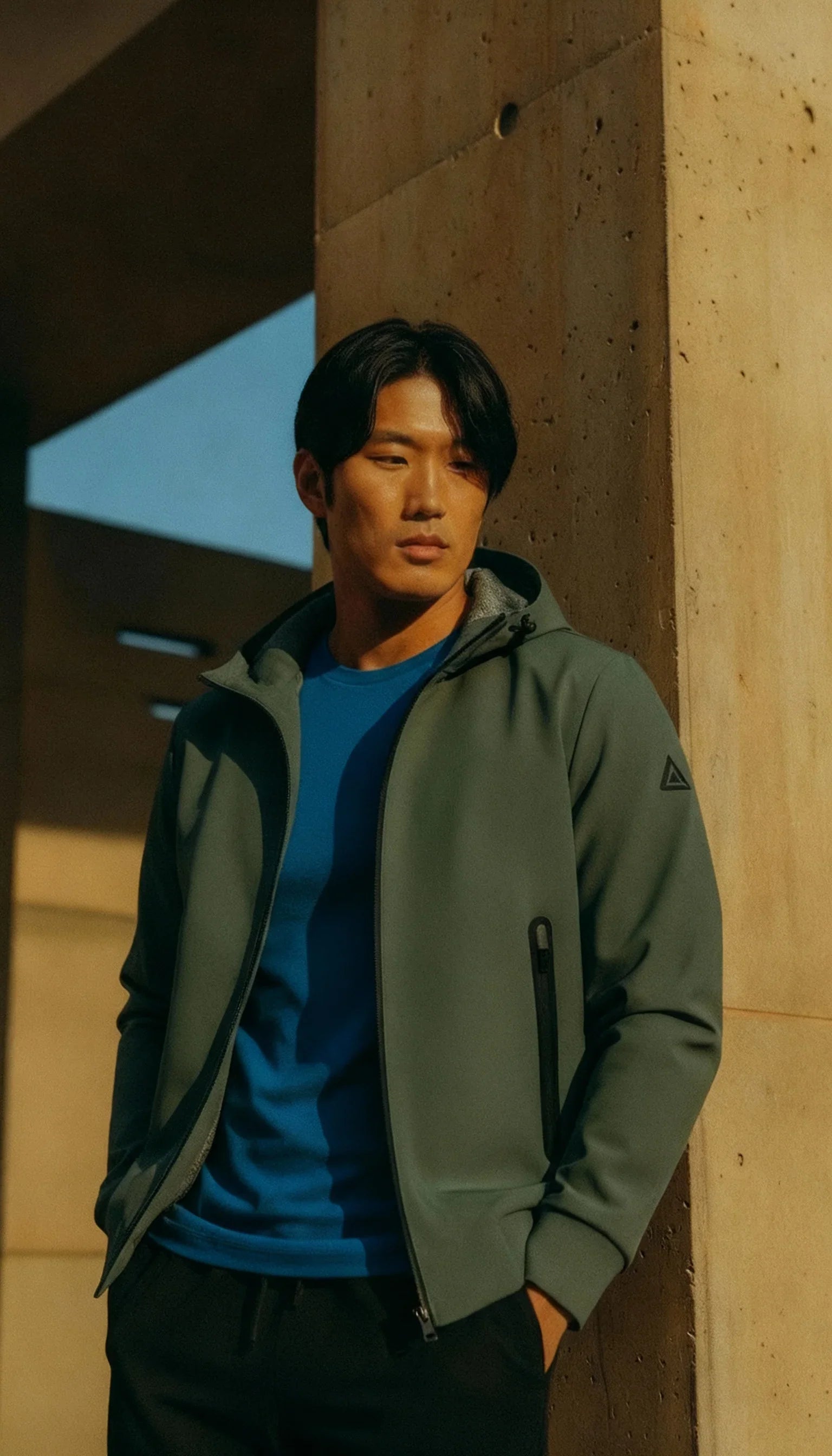 Modello con giacca militare verde e maglietta blu, look casual da uomo all'aperto.
