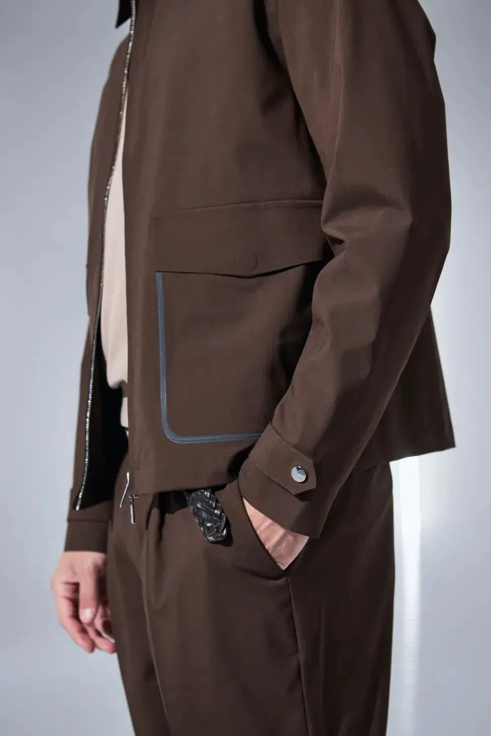 Giacca e pantaloni da uomo marroni, stile elegante primaverile, dettaglio tasca con bordo a contrasto.
