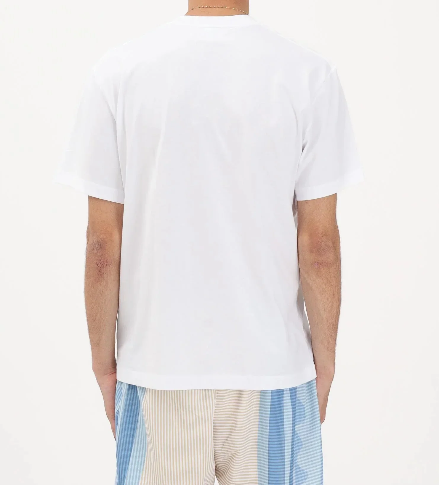 Uomo di spalle indossa t-shirt bianca e pantaloncini estivi a righe blu e beige