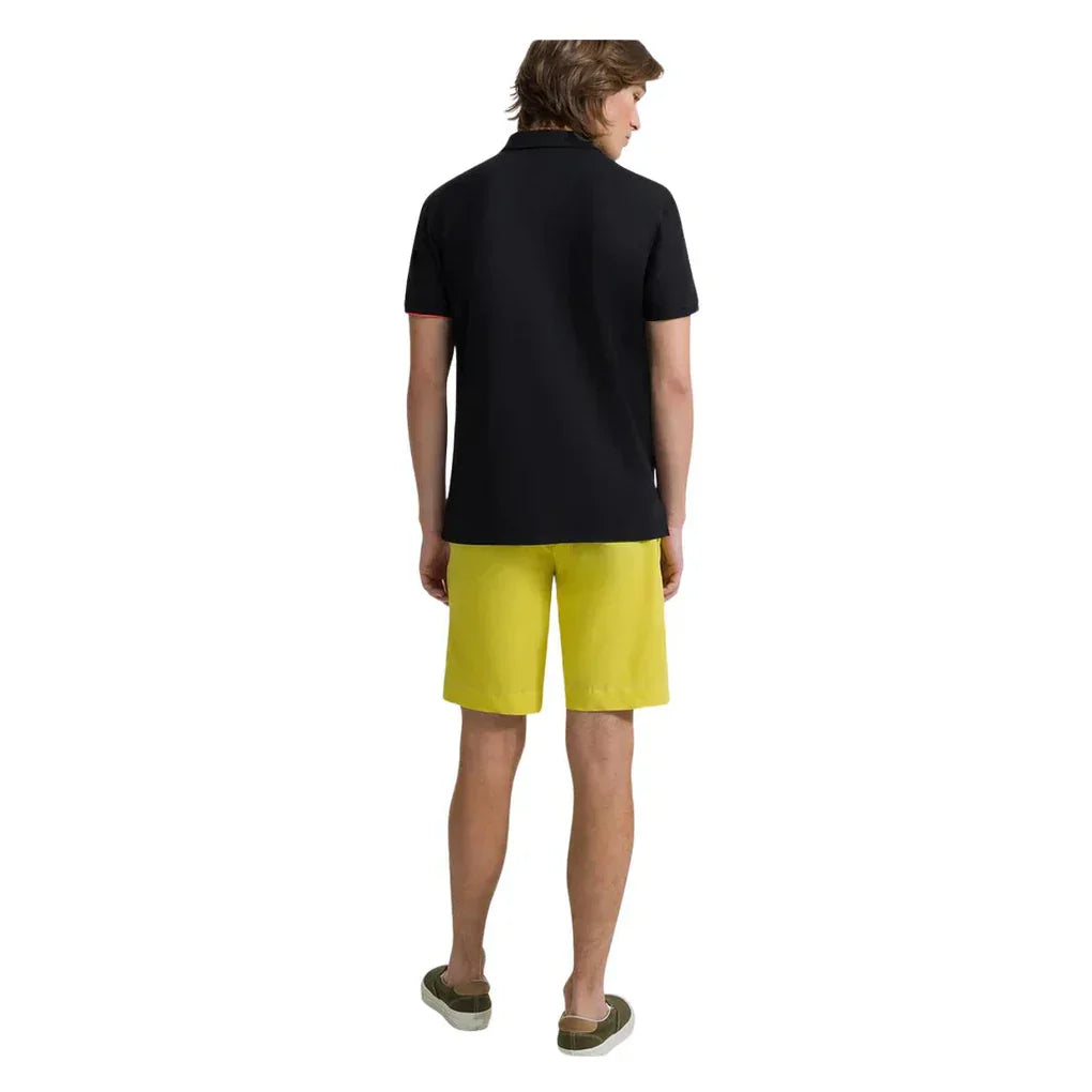 uomo di spalle con polo nera e bermuda gialli, abbigliamento casual estivo