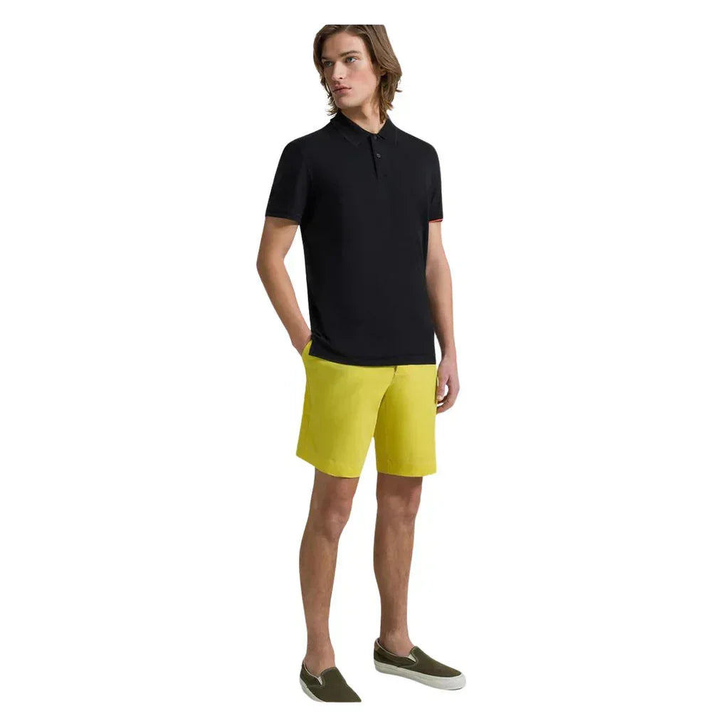 Modello uomo con polo nera, bermuda gialli e slip-on verde, abbigliamento estivo casual.