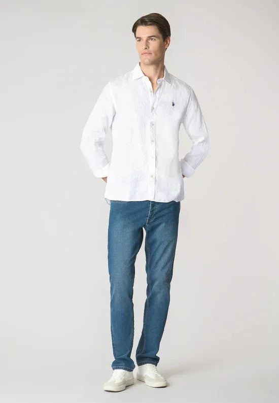 Modello indossa camicia bianca in lino da uomo, jeans slim fit e sneakers bianche.