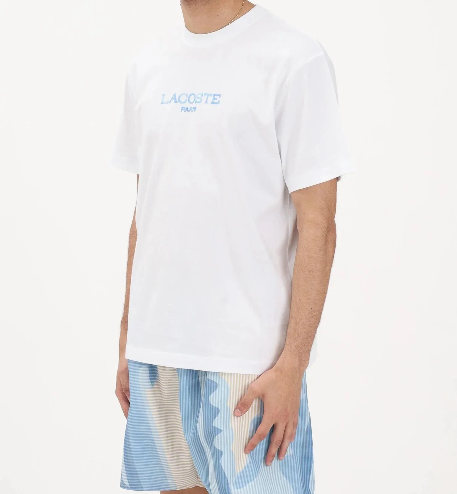 Maglietta bianca uomo Lacoste Paris e pantaloncini corti azzurri a righe, moda estiva casual.