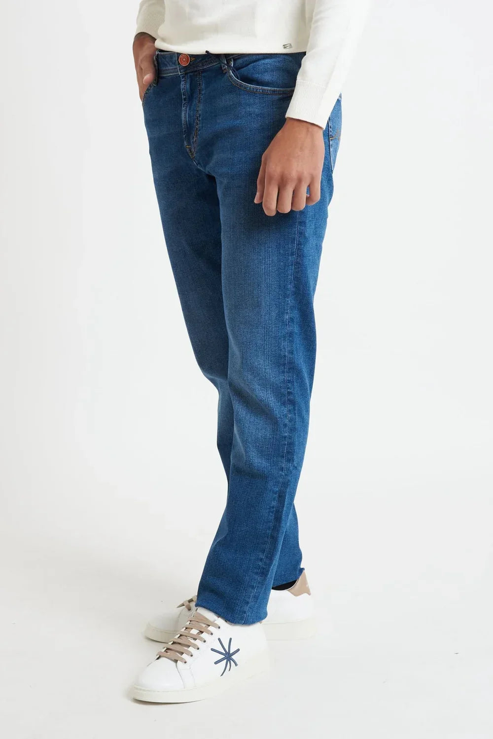 Jeans uomo denim blu, taglio classico, indossati con sneakers bianche su sfondo neutro.