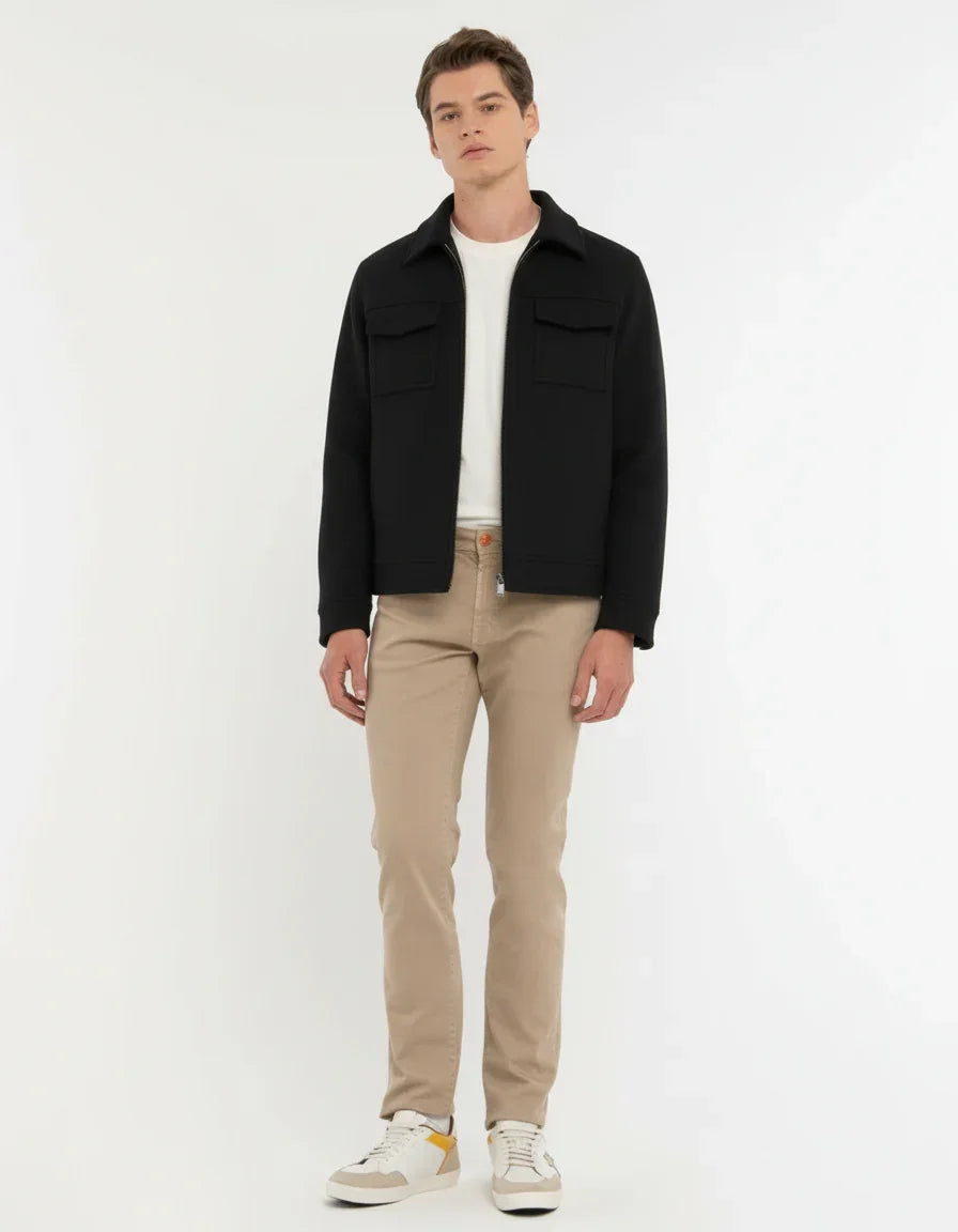 Giacca nera uomo pesante con tasche frontali, abbinata a pantaloni beige e sneakers bianche