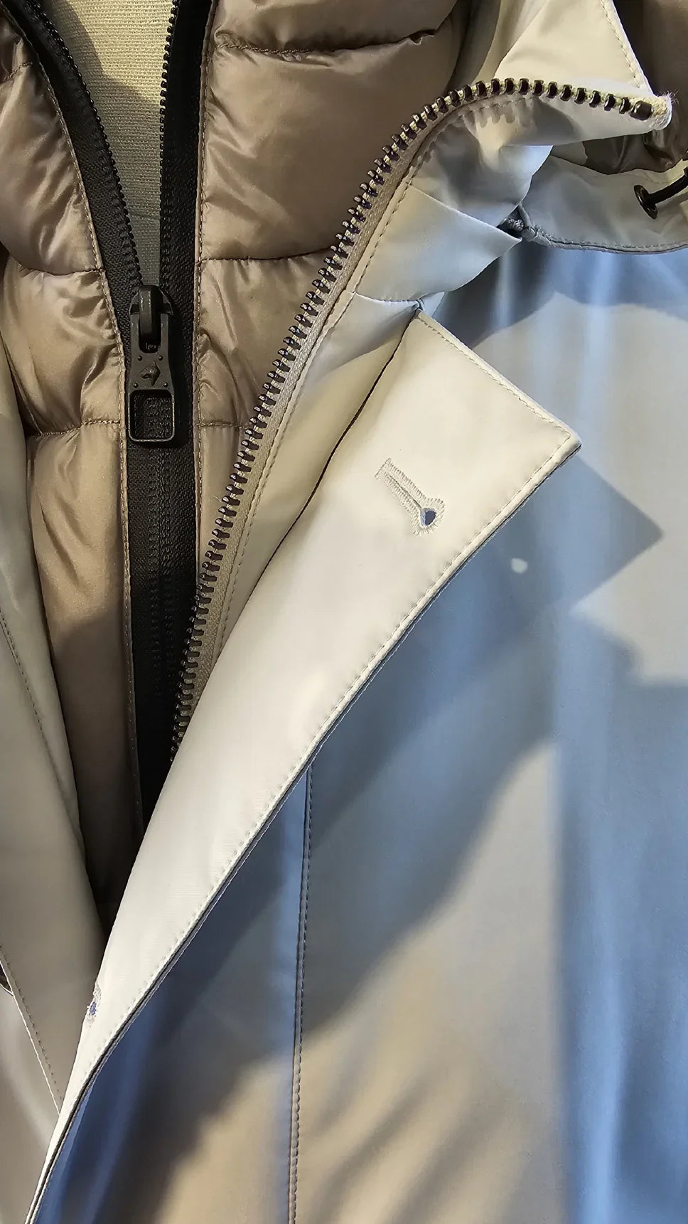 Dettaglio trench uomo avorio con zip e imbottitura interna, abbigliamento elegante.