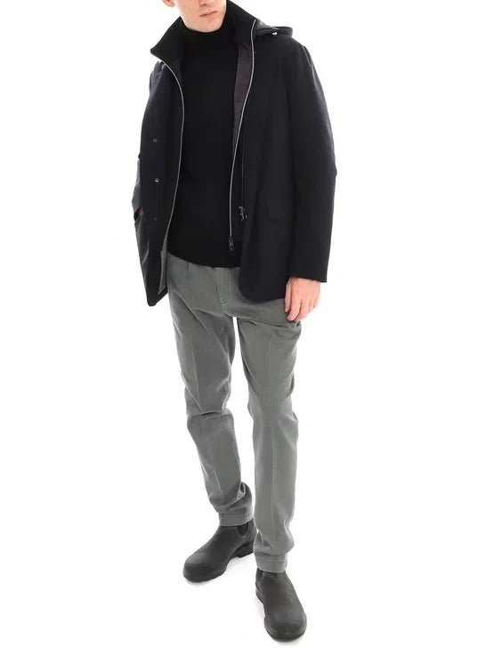 Giacca blu uomo elegante con zip e tasche, indossata con dolcevita nero e pantaloni grigi.