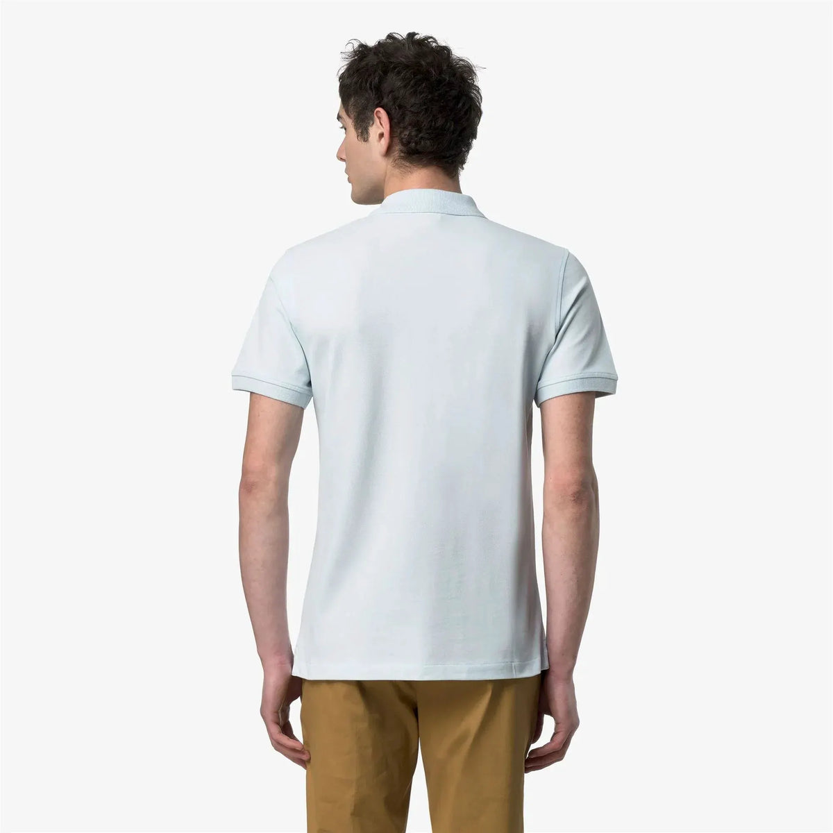 Uomo di spalle indossa polo celeste a maniche corte e pantaloni beige, moda uomo casual.