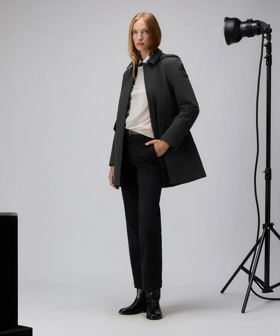 Donna con trench nero slim fit, pantaloni neri e stivaletti, su sfondo studio fotografico