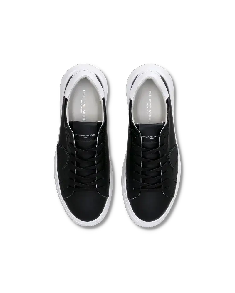 Sneakers uomo nere e bianche con lacci, vista dall’alto, dettagli moderni.