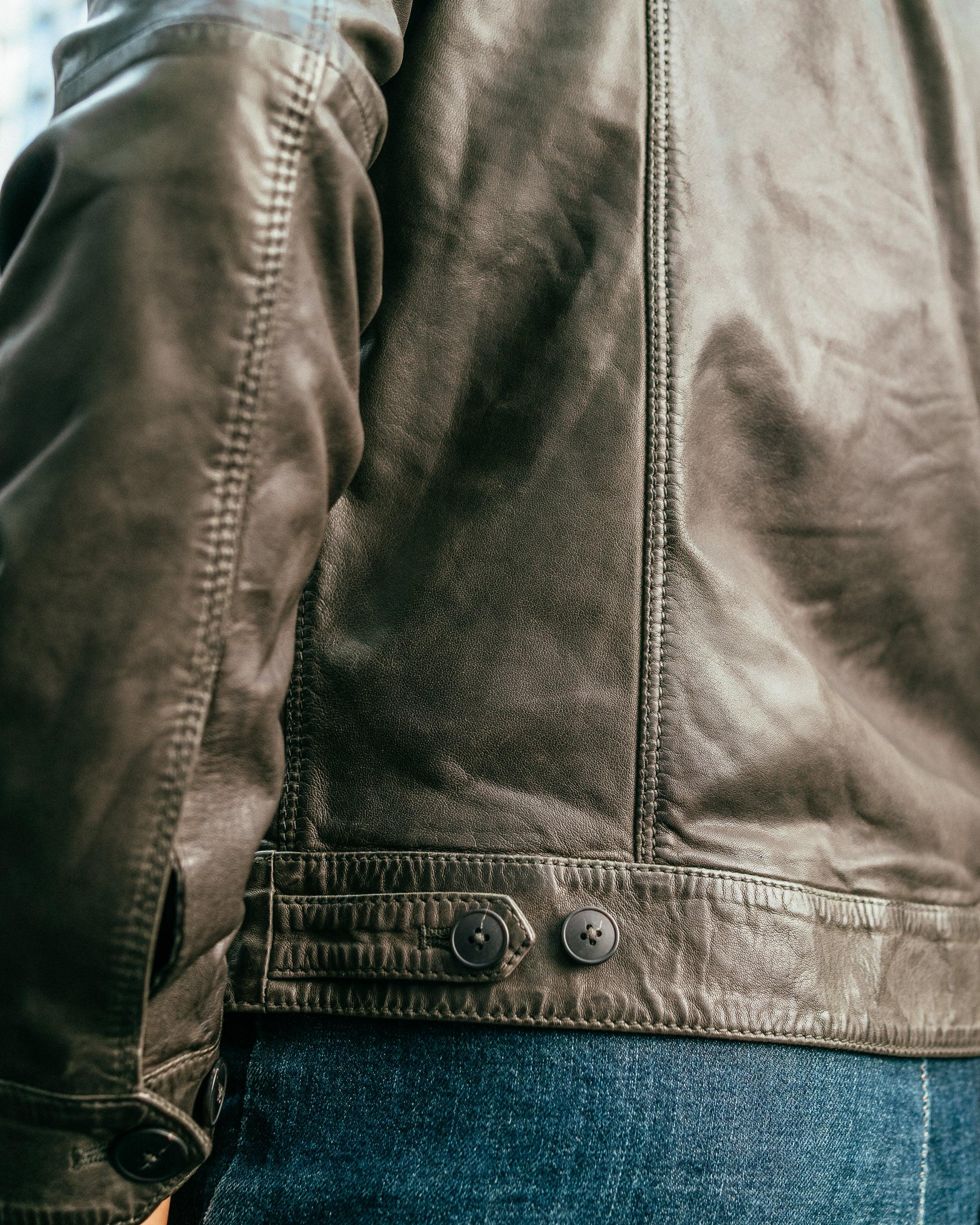 Dettaglio giacca in pelle marrone da uomo con bottoni, abbigliamento moda casual.