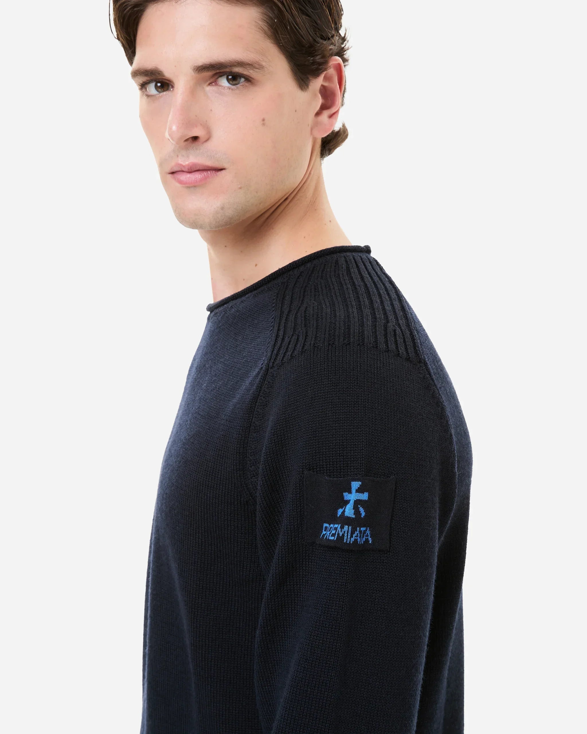 Maglia uomo blu in lana merino con logo sulla manica e dettagli a coste sulle spalle.