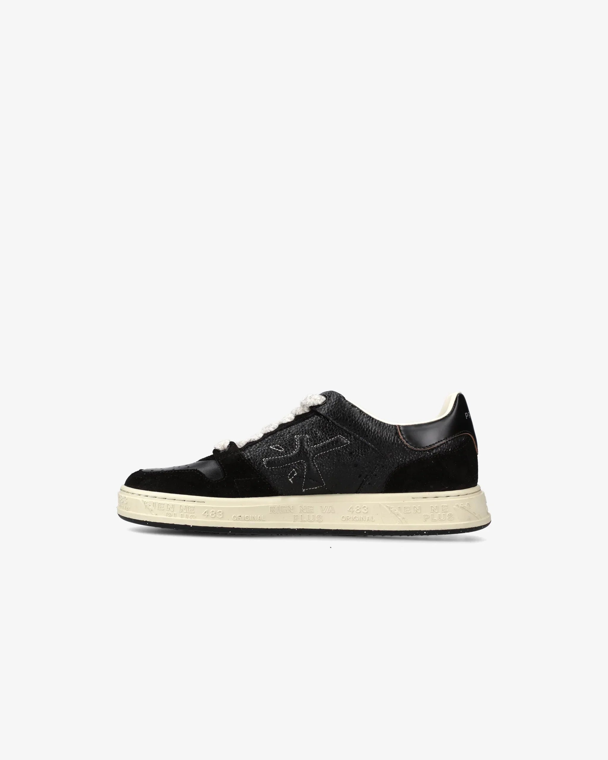 Sneaker nera bassa in pelle con suola beige, dettagli laterali a contrasto, stile casual.