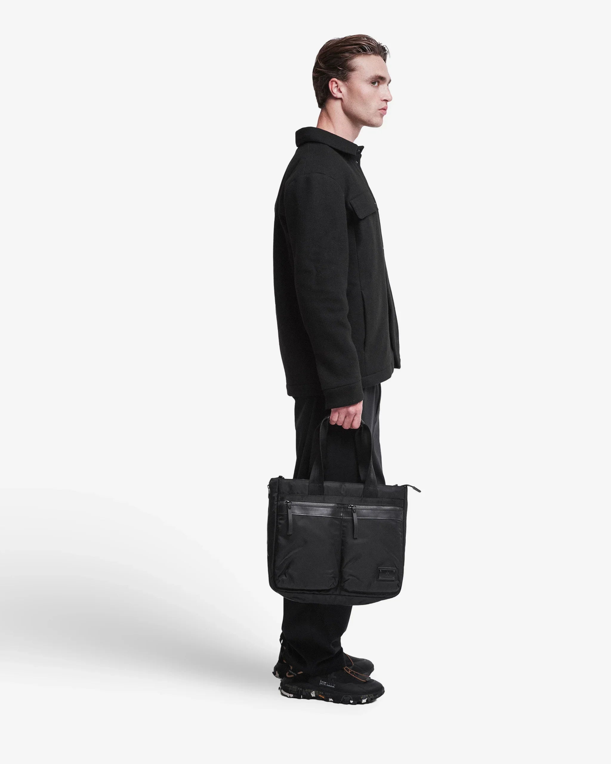 Giacca uomo nera elegante con borsa a mano, look total black casual moderno.