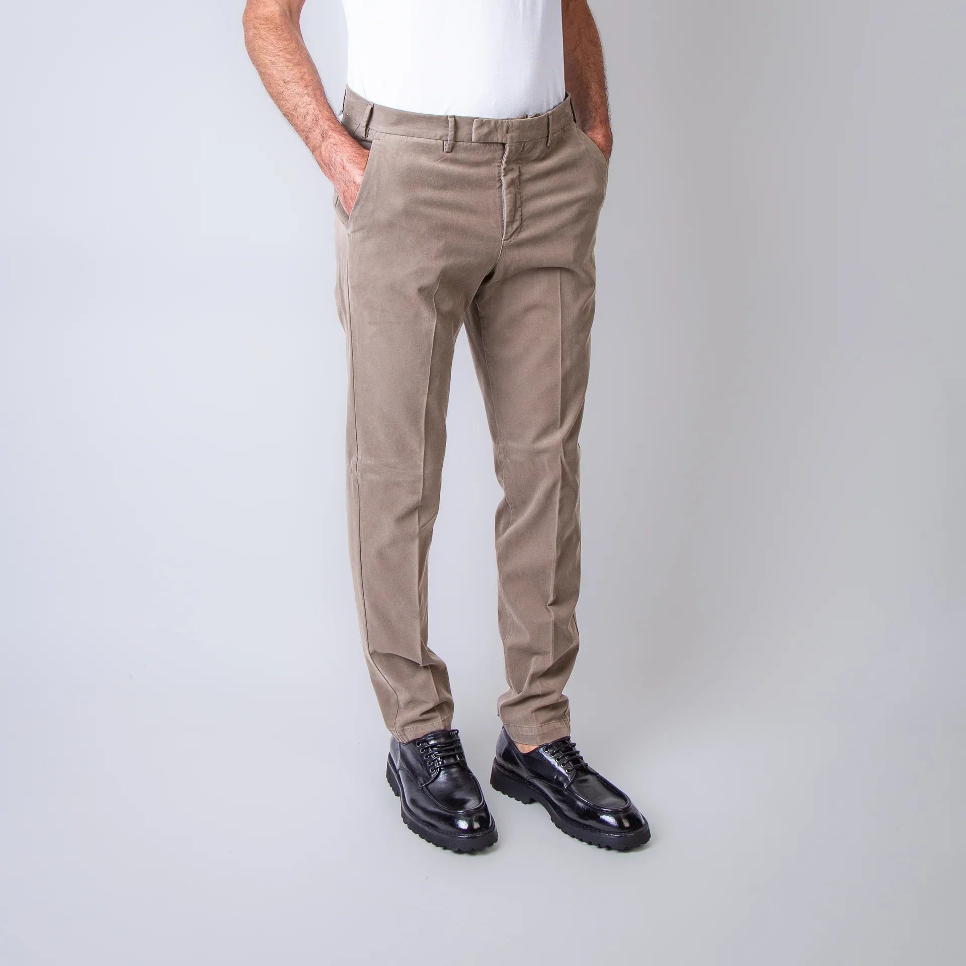 Pantaloni uomo beige eleganti, vestibilità slim, indossati con camicia bianca.