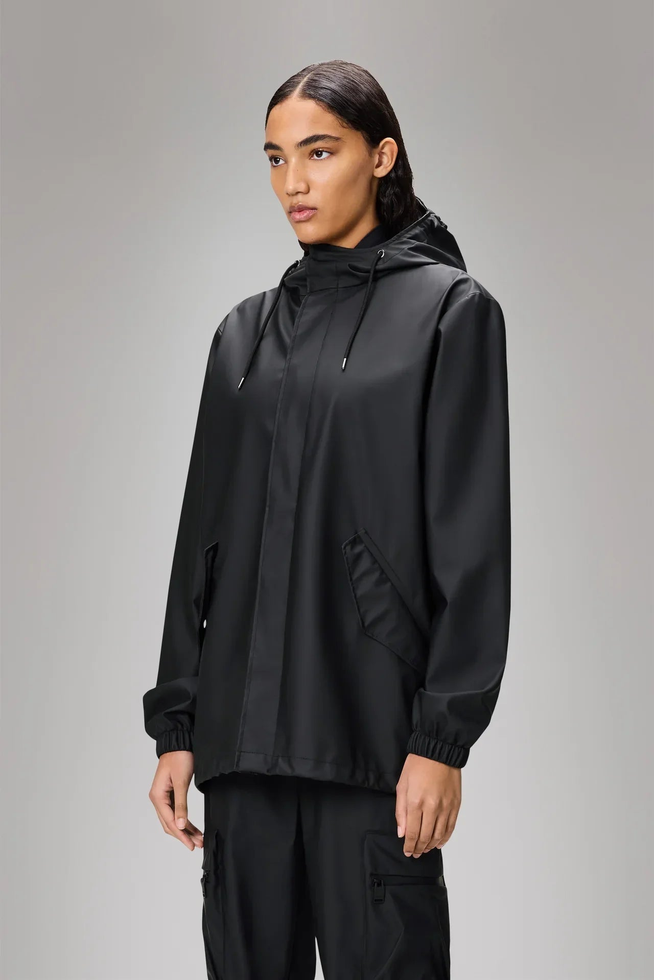 Giacca impermeabile nera da donna con cappuccio, chiusura zip e tasche laterali.
