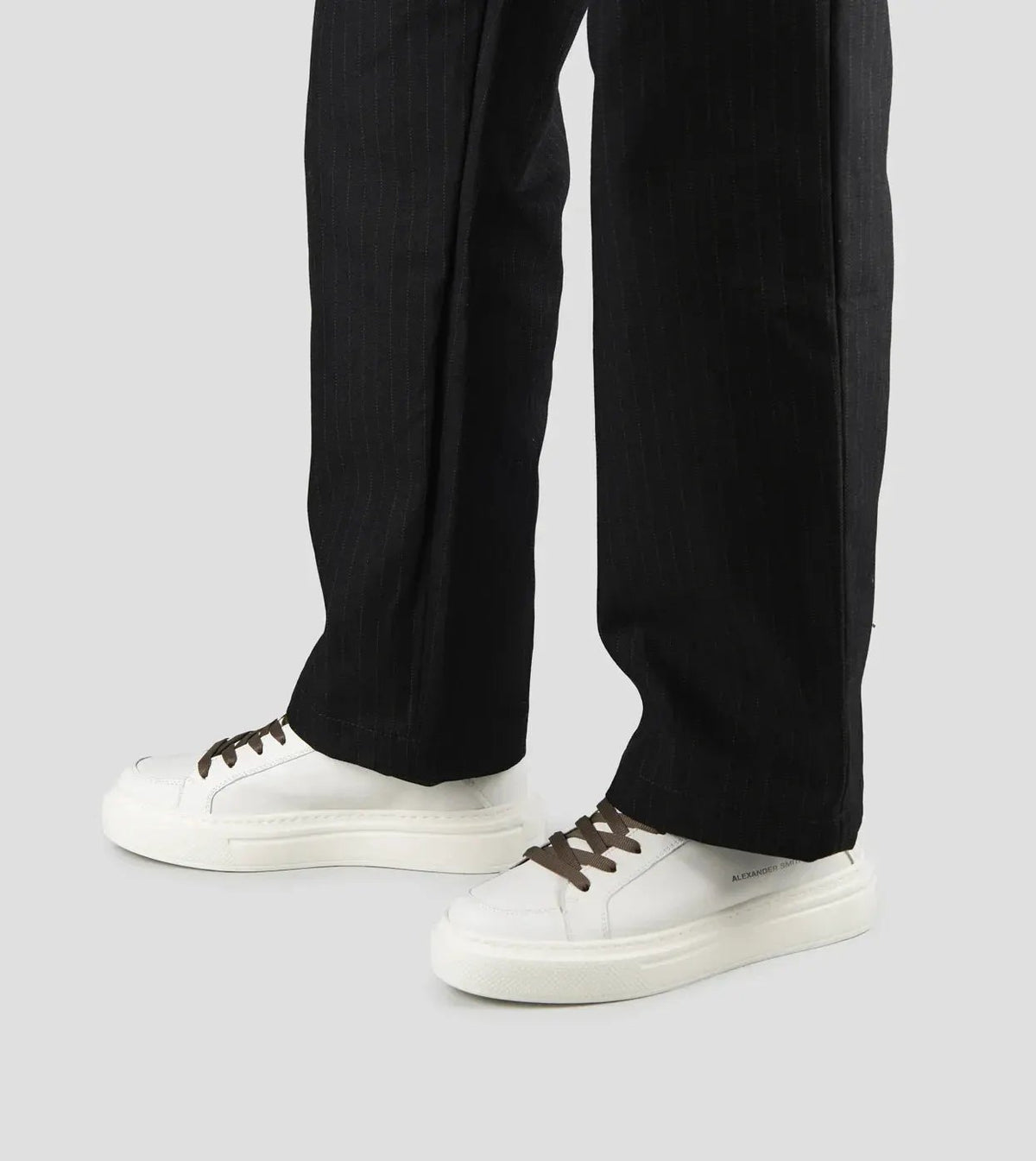 Sneakers uomo in pelle di capra bianca con dettagli verde militare e pantaloni scuri