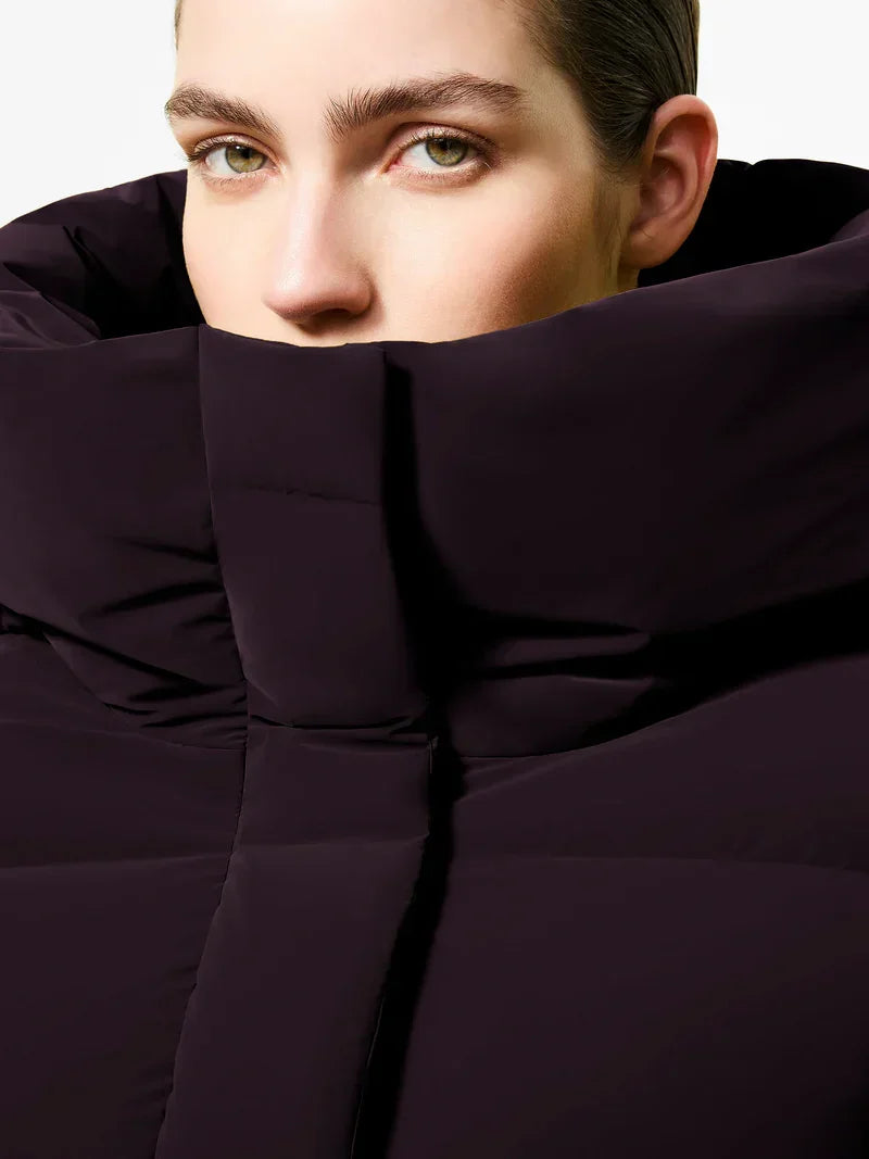 Primo piano di donna con piumino tubico viola scuro, collo alto, moda invernale elegante.