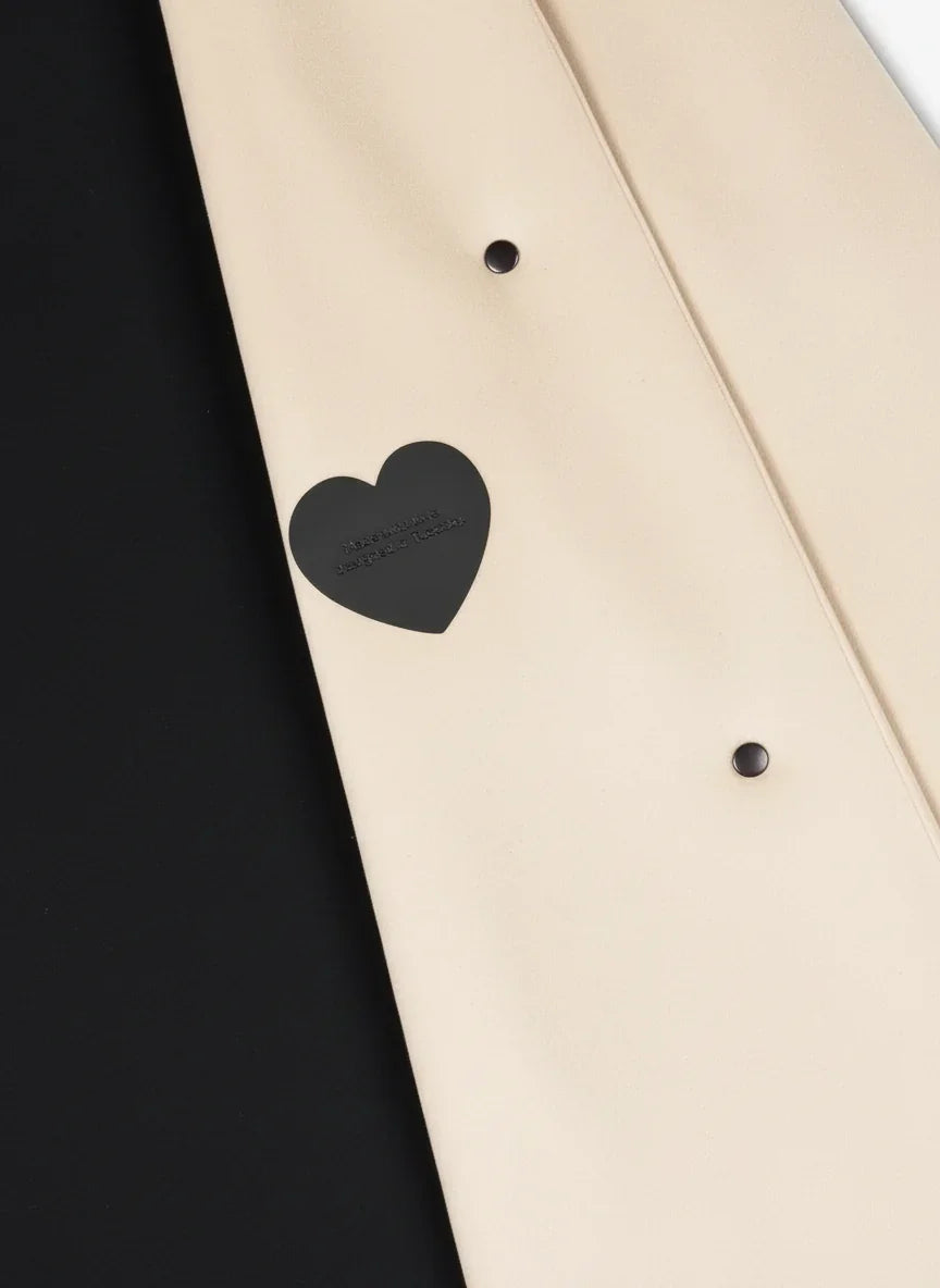 Dettaglio di cappotto donna beige in velour con borchie nere e cuore nero decorativo