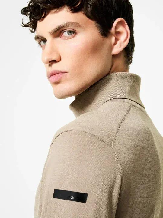 Maglione dolcevita beige uomo in maglia merino, dettaglio patch sulla manica sinistra.