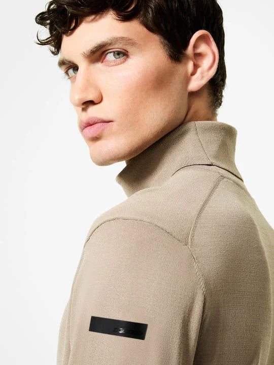 Maglione dolcevita beige uomo in maglia merino, dettaglio patch sulla manica sinistra.