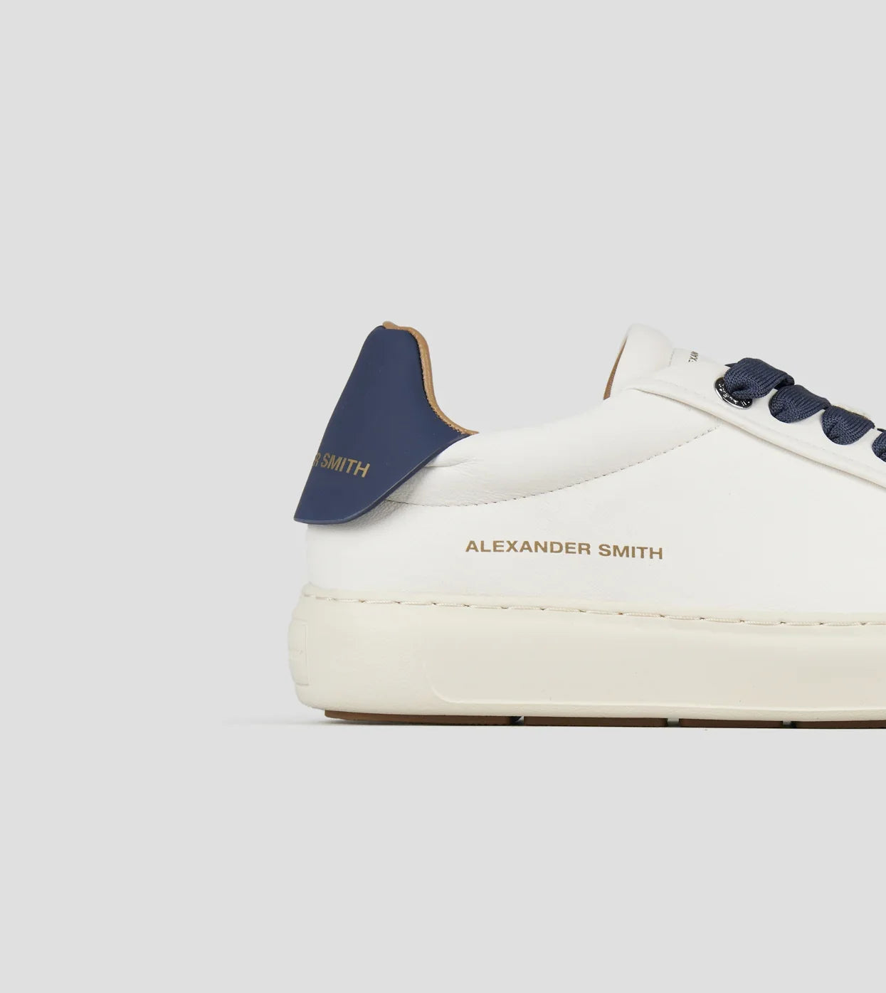 Sneaker uomo in nappa bianca con tallone in pelle blu e lacci blu, suola piatta chiara.