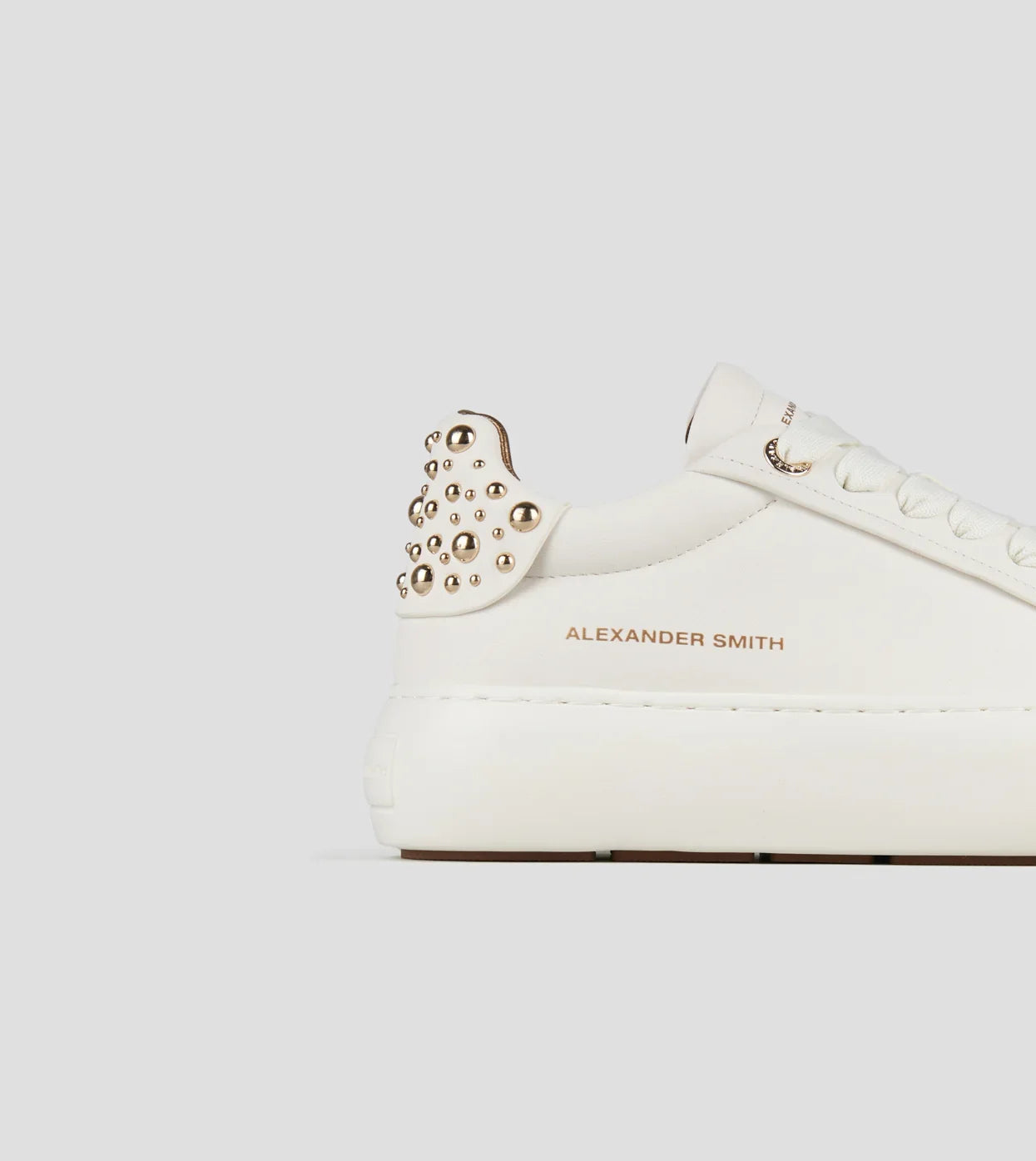 Sneaker donna in pelle bianca con borchie dorate sul tallone e suola platform